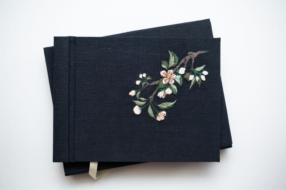 a hand-made photo album decorated with an embroidered design of apple blossom