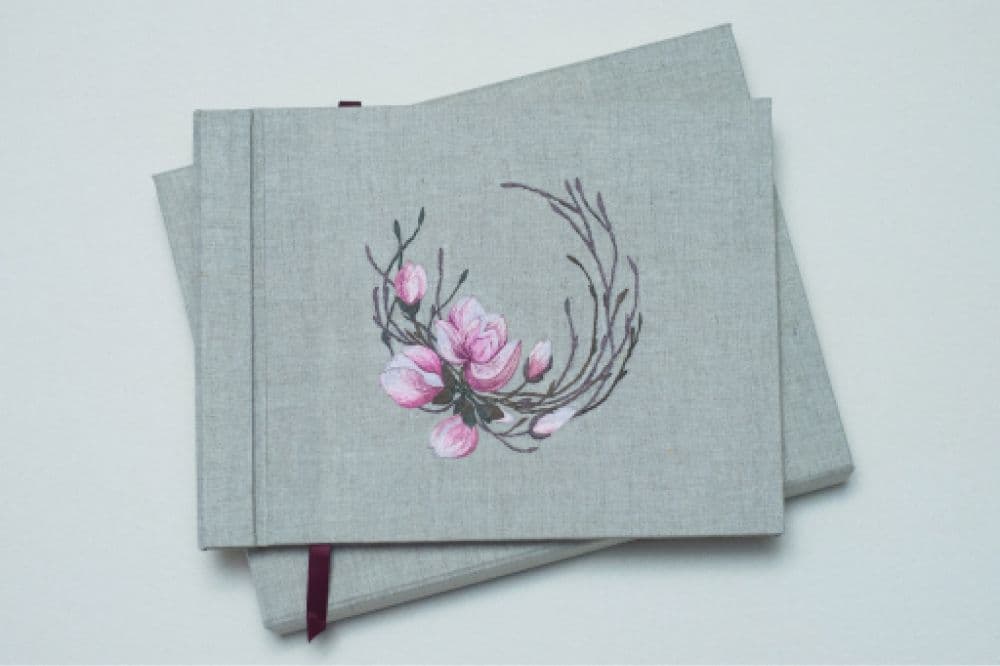 a hand-made photo album decorated with an embroidered design of magnolia blossom