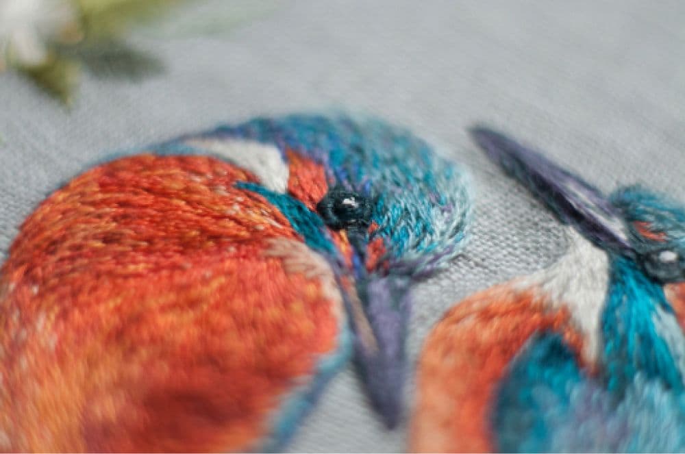 a close-up of a hand-made photo album decorated with an embroidered design of two Kingfishers