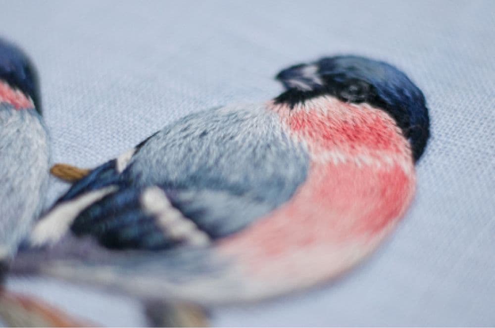 a close -up of a hand-made photo album decorated with an embroidered design of two snowbirds