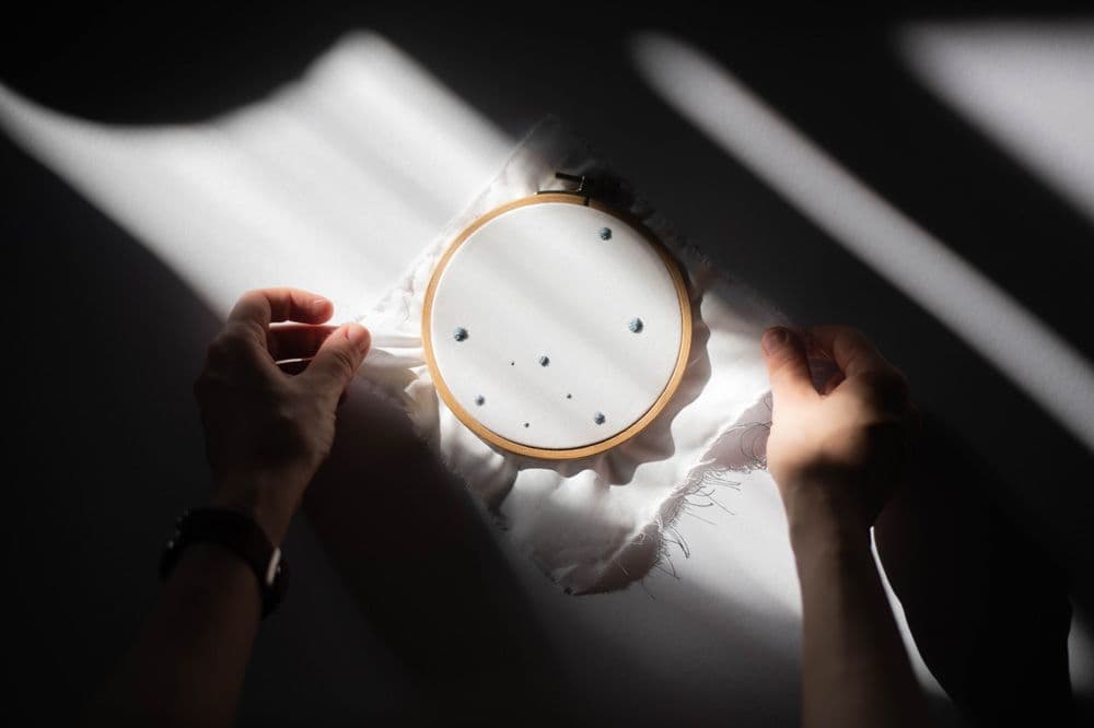 an embroidery hoop with a piece of cloth stitched with dots is laying on the floor