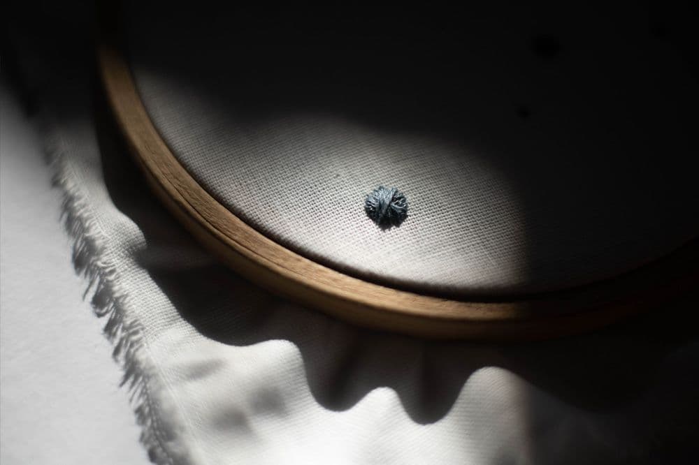an embroidery hoop with a piece of cloth stitched with dots is laying on the floor