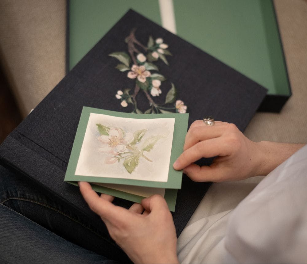 a photo album with an embroidered design on the cover is held in hands
