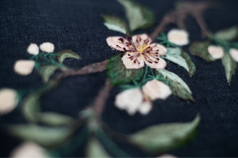 a close-up of a hand-made photo album decorated with an embroidered design of apple blossom