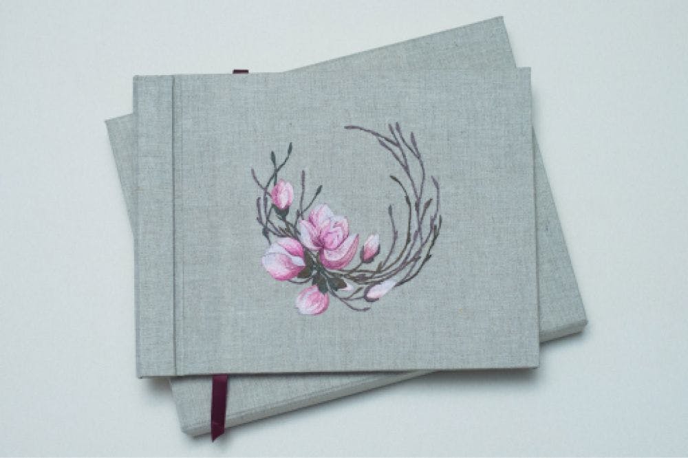 a hand-made photo album decorated with an embroidered design of magnolia blossom