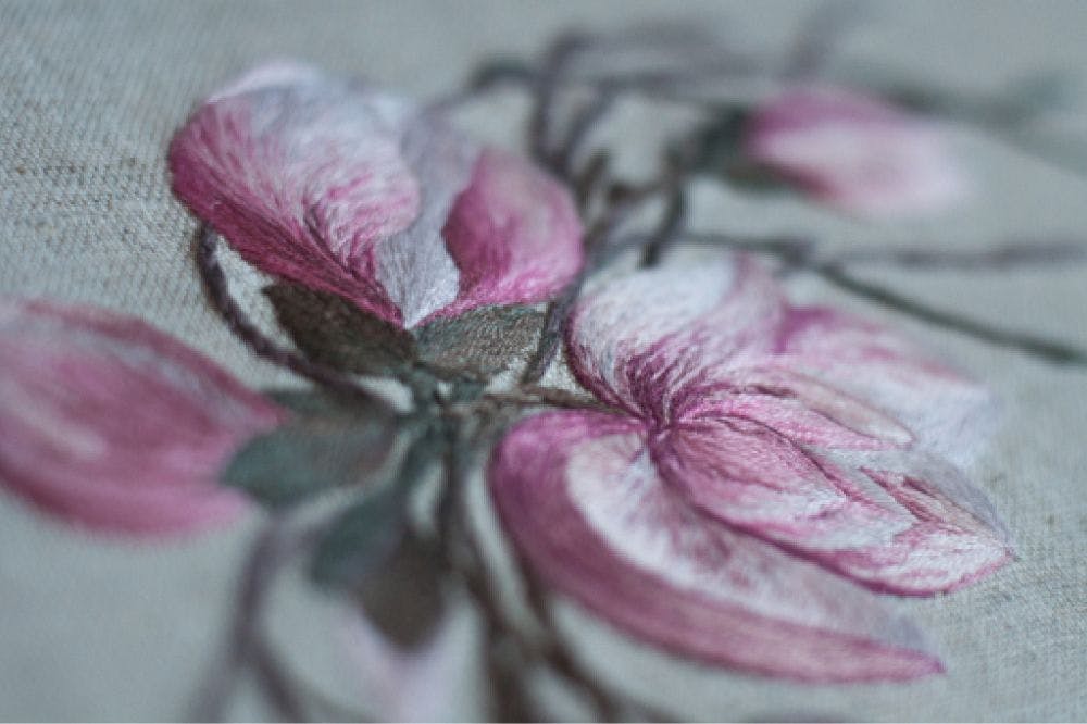 a close-up of a hand-made photo album decorated with an embroidered design of magnolia blossom