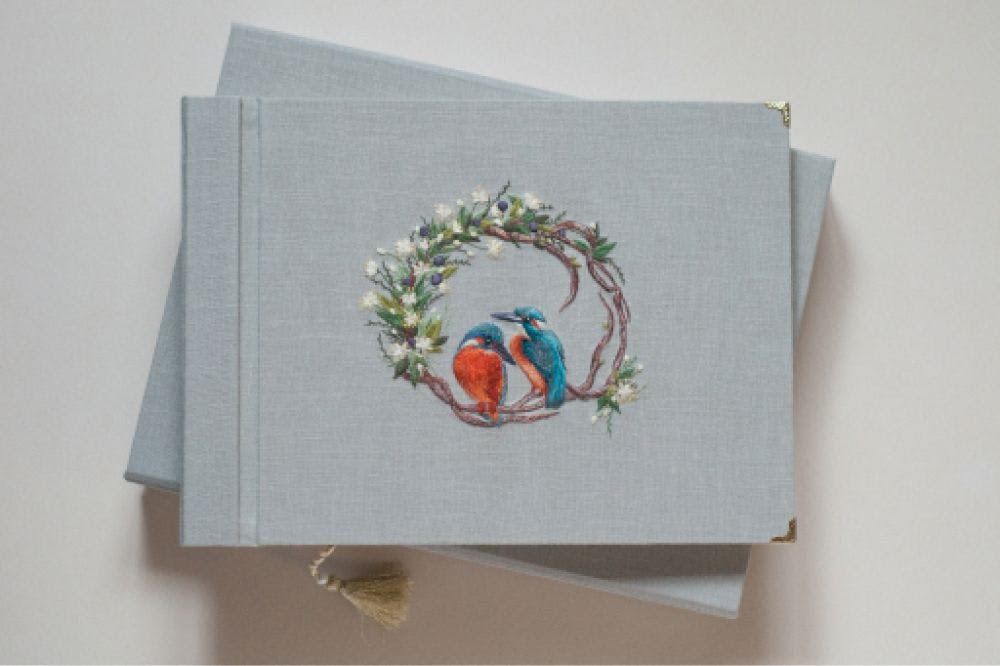 a hand-made photo album decorated with an embroidered design of two Kingfishers