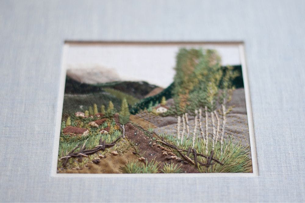 a close-up of a hand-made photo album decorated with an embroidered design of a mountain view