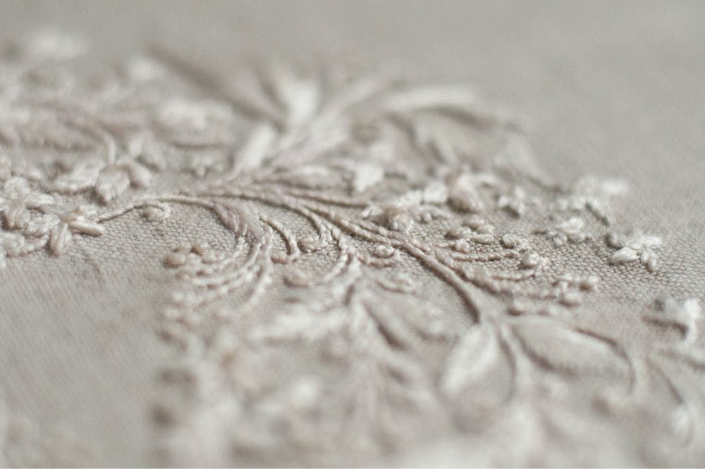 a close-up of a hand-made photo album decorated with whitework made in raw silk