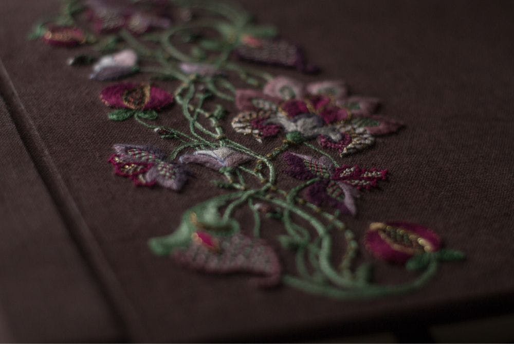 a close-up of a hand-made photo album decorated with Jacobean embroidery motifs
