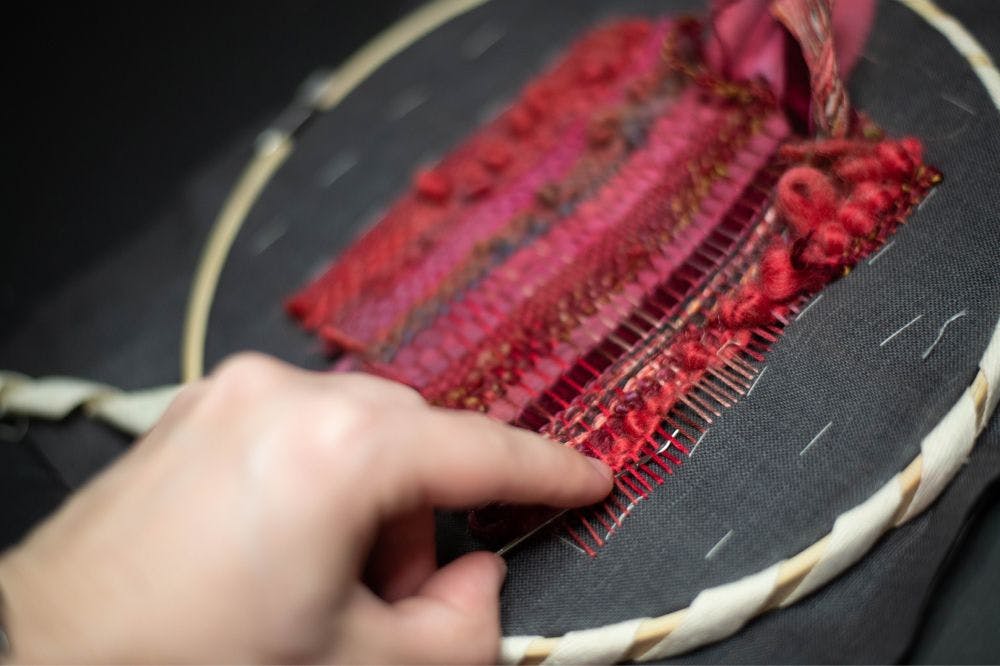 a hand weaving the thread