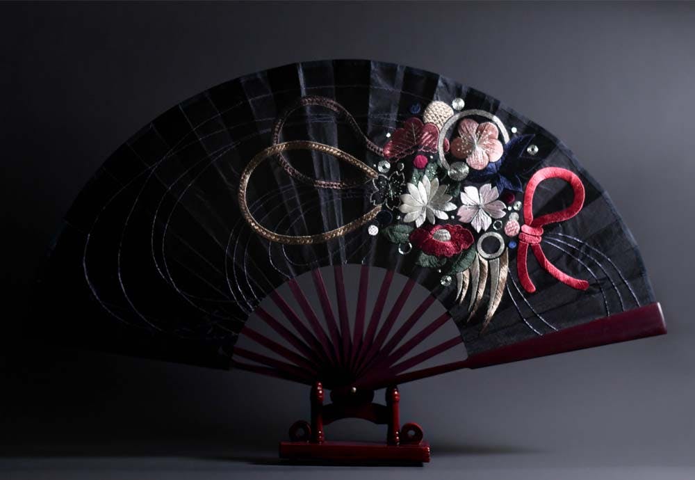 an embroidered fan on a wooden stand 