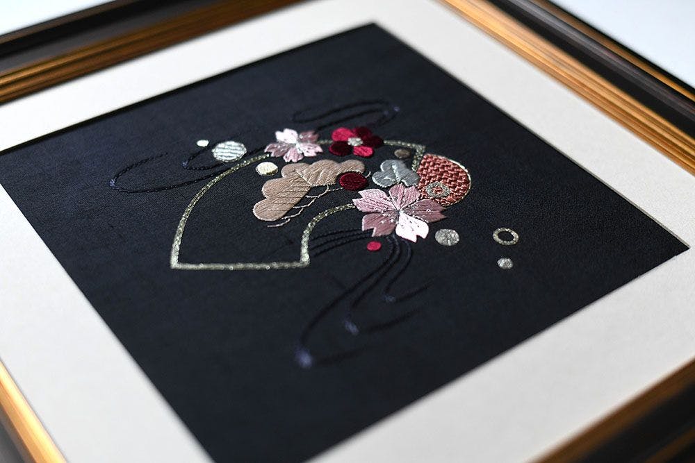 a framed piece of silk embroidery close-up