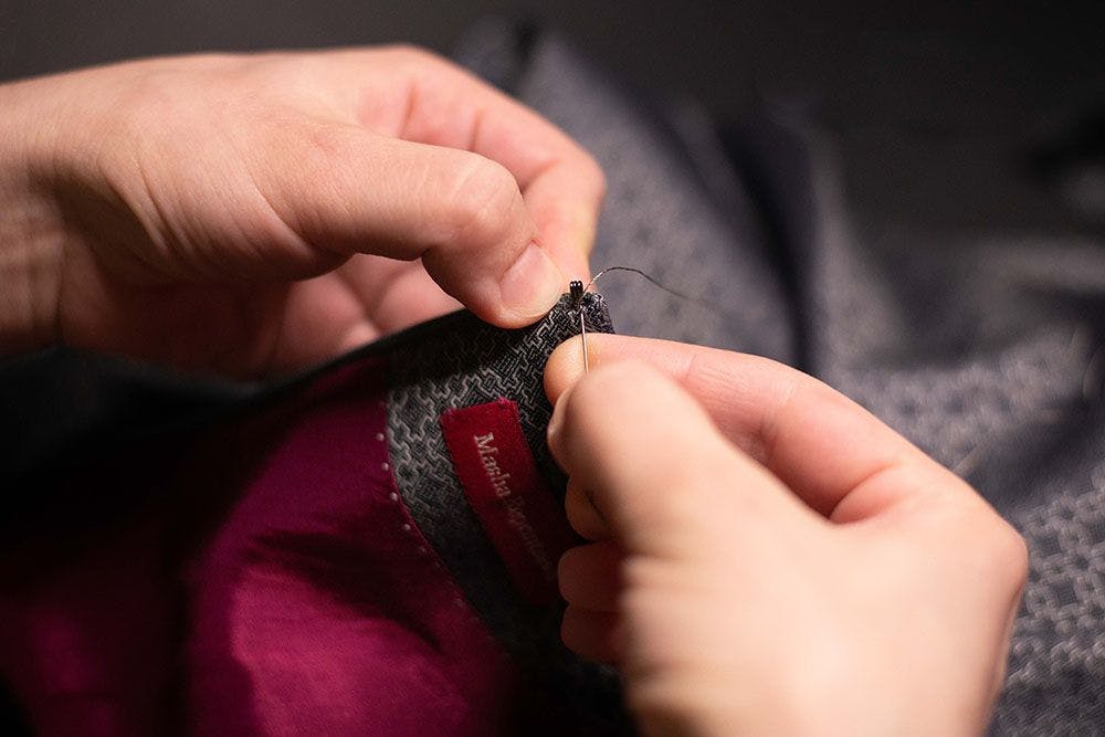 a pair of hands sewing in a hook-fastener to the dress