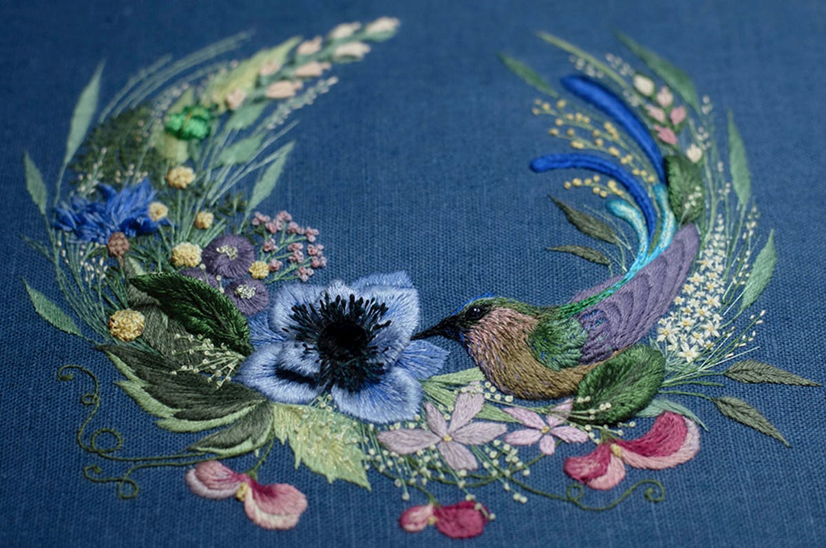 a close -up of a hand-made photo album decorated with an embroidered bird and flower wreath